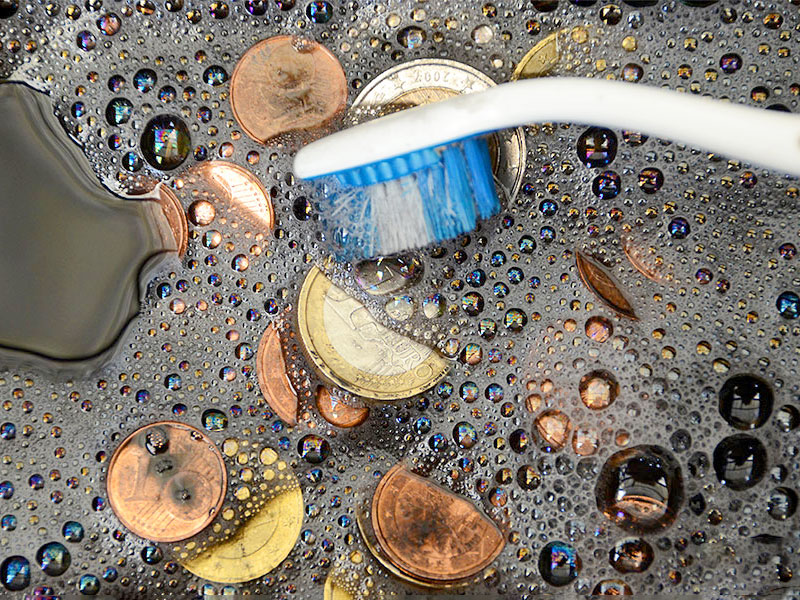 Münzen reinigen in einem Seifenbad mit einer weichen Zahnbürste